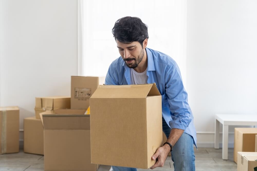Man picks up a box as he is moving