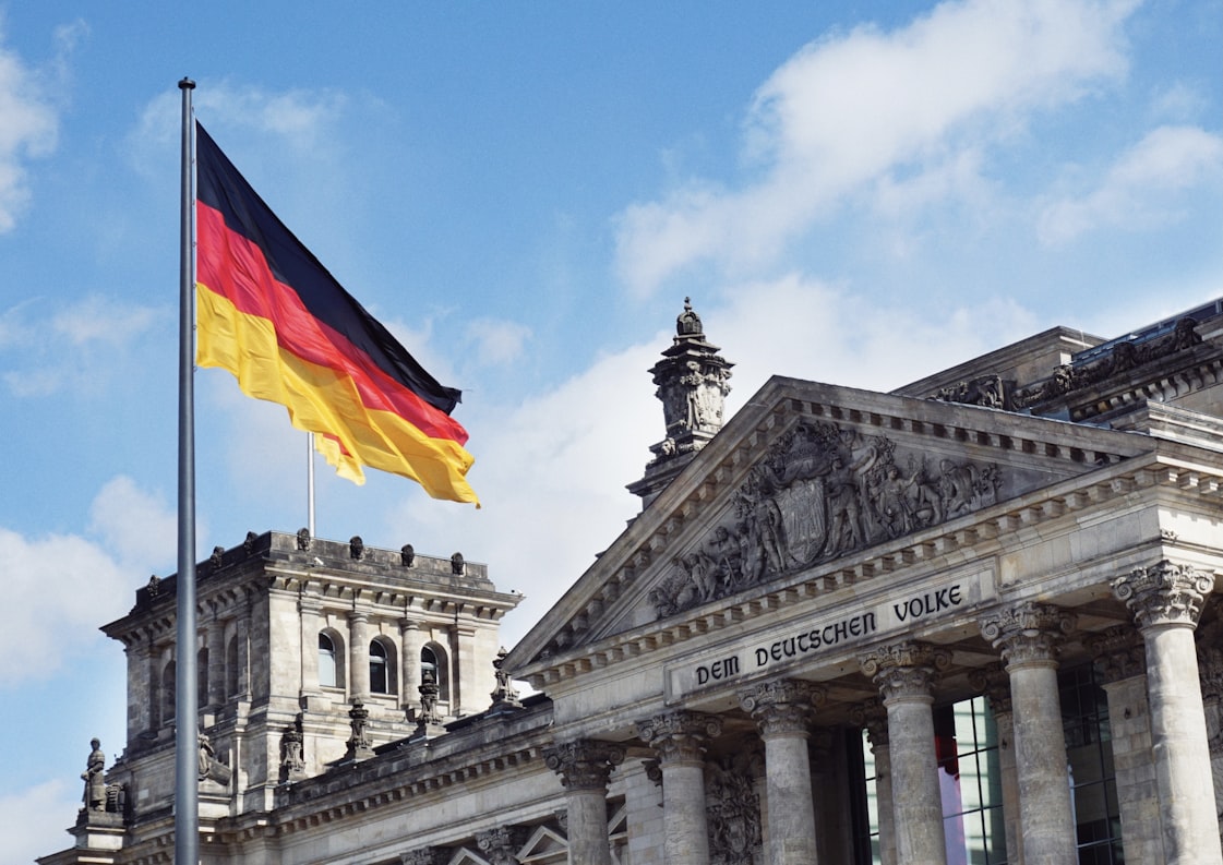 A german flag, waving in front of an ornate building in Berlin, Germany