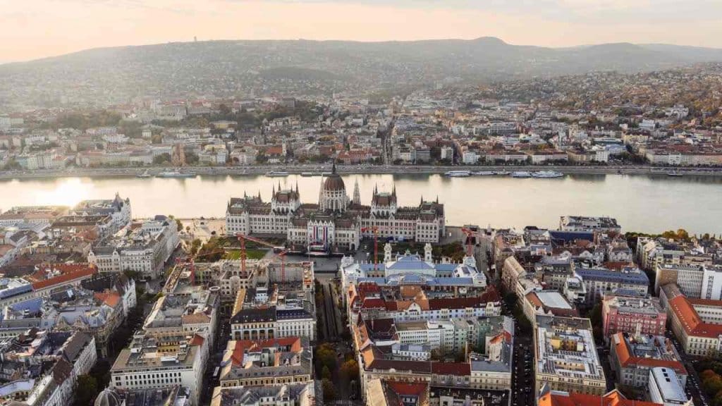 An aerial view of Budapest with a river flowing behind the Hungarian parliament