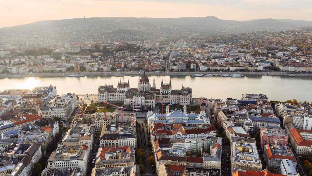 An aerial view of Budapest with a river flowing behind the Hungarian parliament