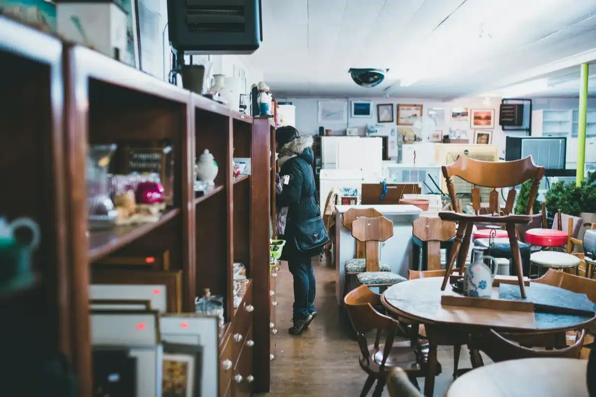 A woman standing beside a shelf sorting her stuff with a lot of furniture in the background