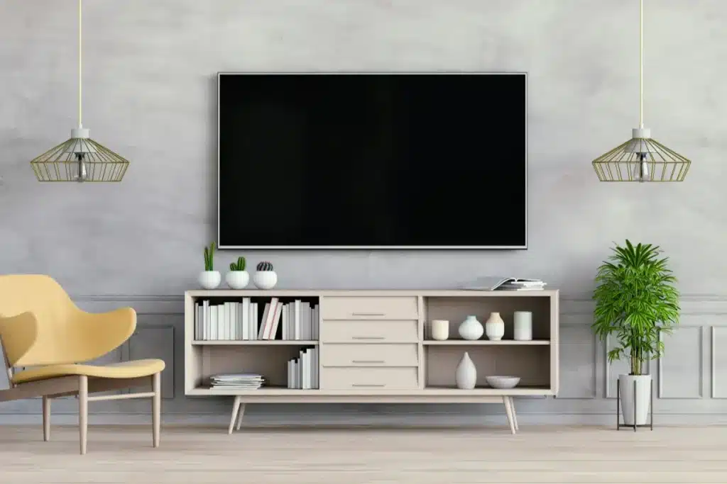 Flat screen TV mounted above a low media console in a living room with shelves